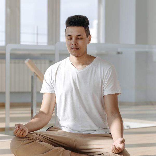 Person meditating peacefully in a bright, sunlit room.